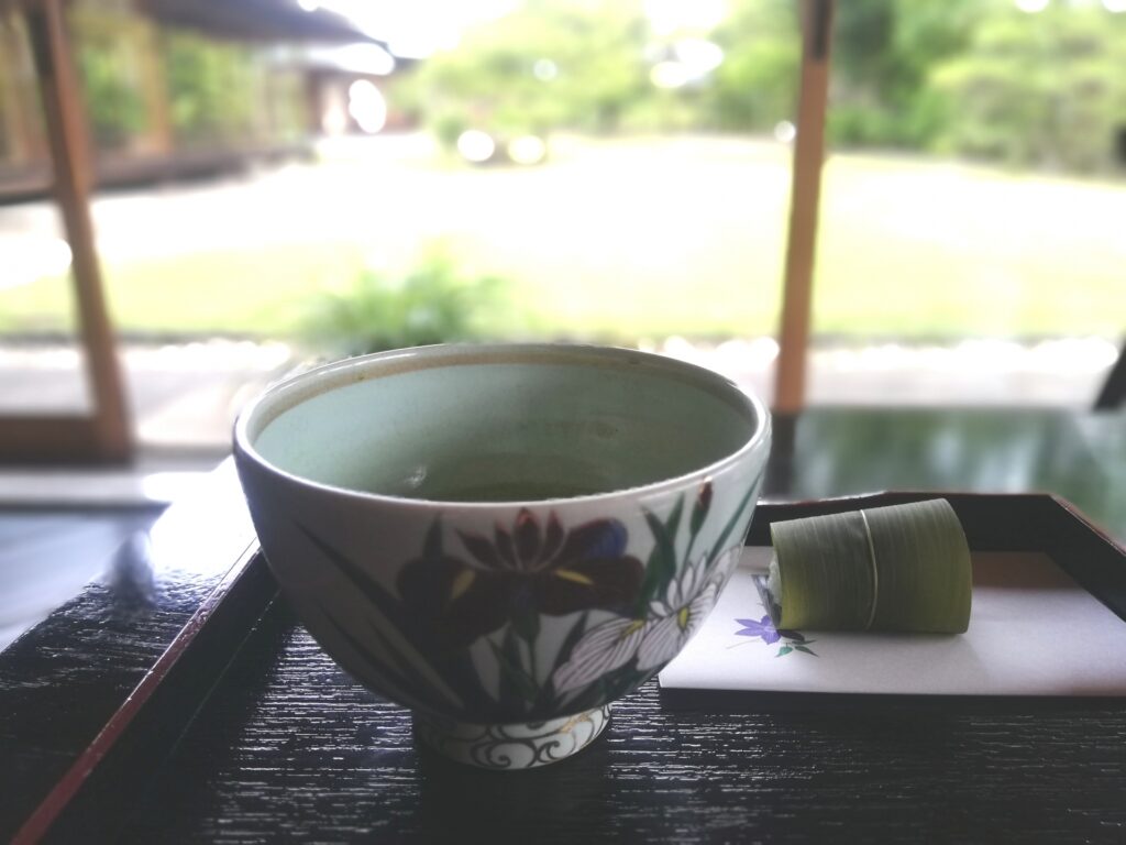 日本庭園を背景に、抹茶碗1個が静かに置かれた茶道具のイメージ。茶碗の種類や選び方を初心者から愛好家まで解説するガイド。