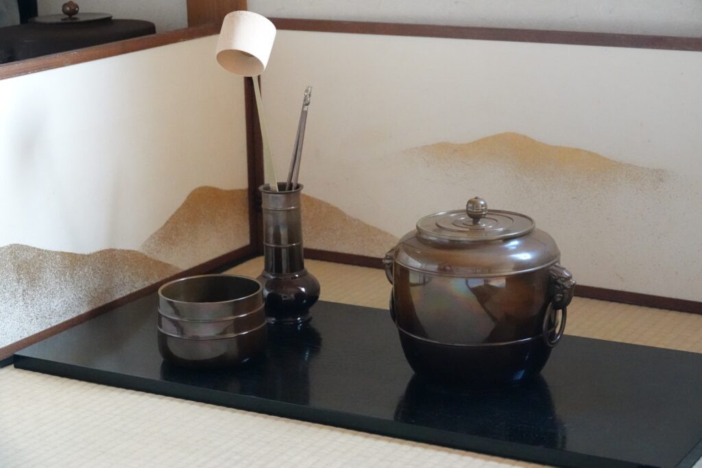 茶釜や柄杓などの茶道具が並ぶ茶室の風景。茶道具買取を考える際に重要な道具の一例。