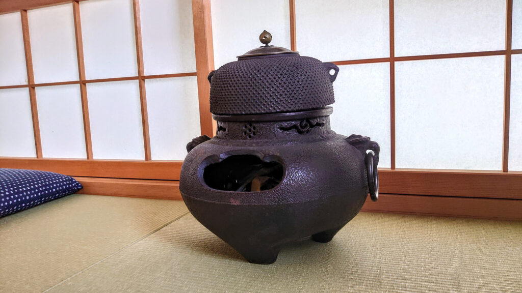 和室に置かれた伝統的な茶釜。茶道で使われる鉄製の茶釜で、買取査定時に価値を決める重要な要素となる。共箱や鑑定書があると査定額が上がることも。茶釜の買取や査定を検討する方へ向けた情報を提供。